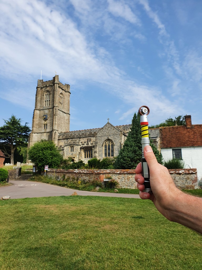 View of the church at Aldboune, with a hand holding a sonicscrew driver aloft