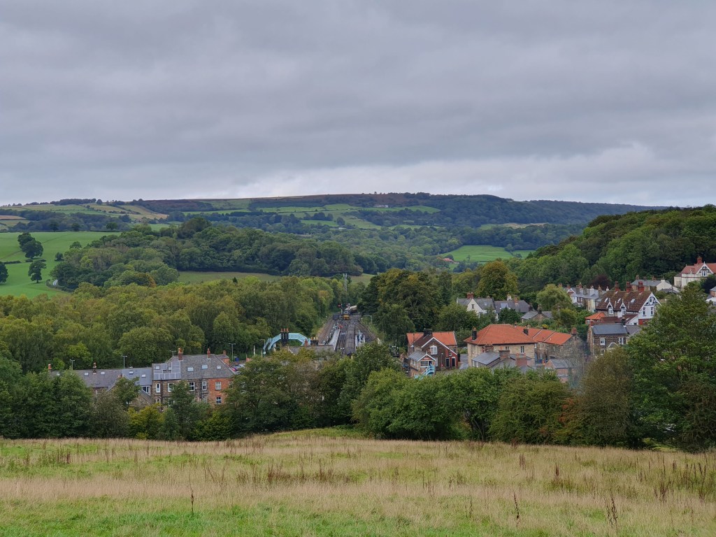 Green hills with buildings and a railway line visible in the middle