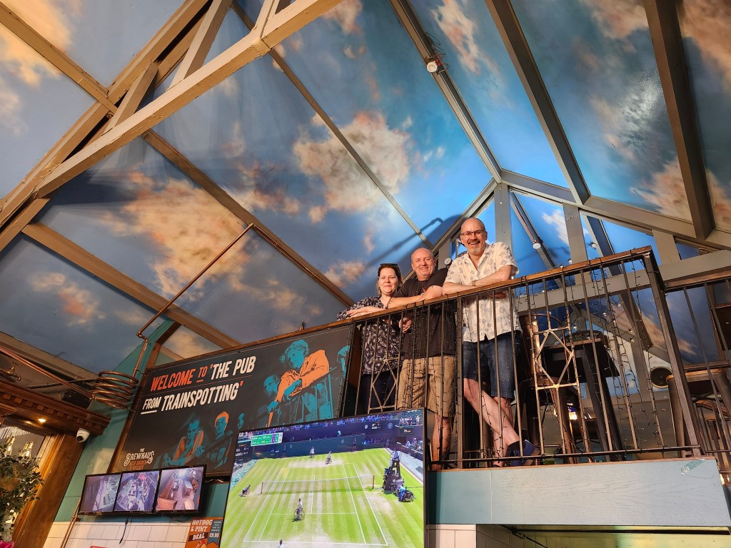 Three people looking over a balcony